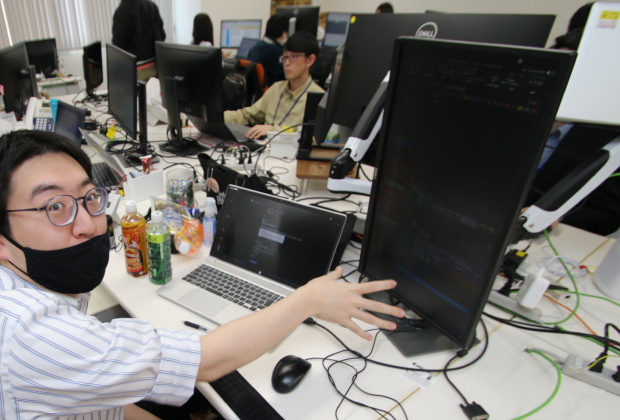 縦長のモニターでコードを読む社員